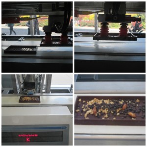 The machine uses suction to pick up the candy bar base and put it on the conveyor belt. Machines deposit the toppings in the bar. Copyright Deborah Abrams Kaplan